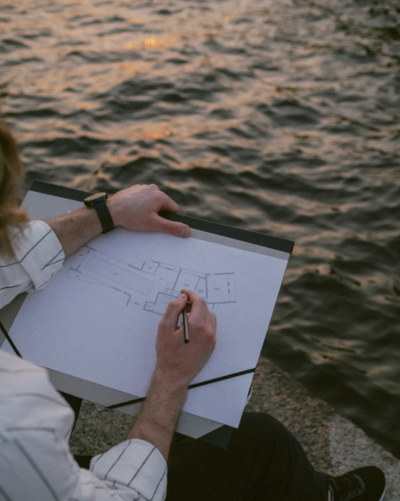 A designer sketching a garden layout on a clipboard outdoors