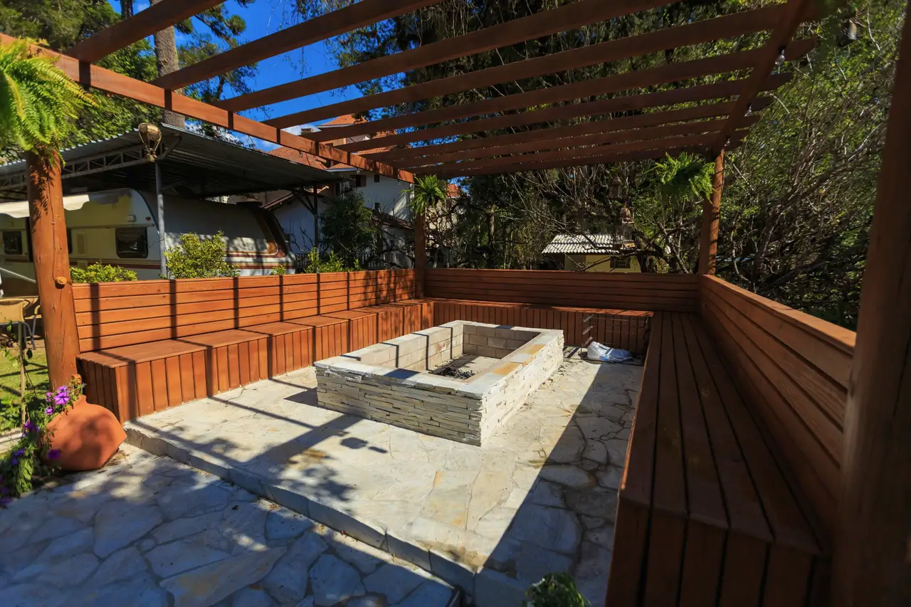 Stone patio under a pergola with a fire pit